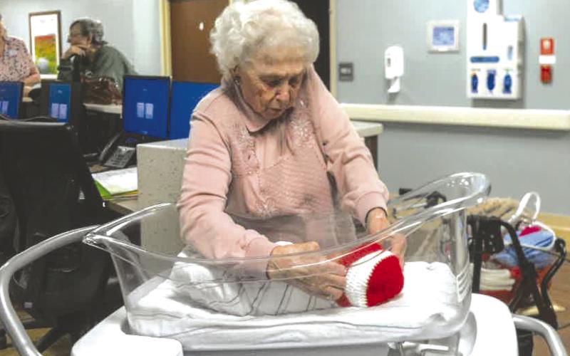 Columbus resident Ruby Wright places the red and white Valentine’s Day cap on Afredo Rodriguez. She has created over 2,000 caps for babies at Freeman Hospital in Joplin, Mo. She is working her way toward 3,000 now. Courtesy photo.