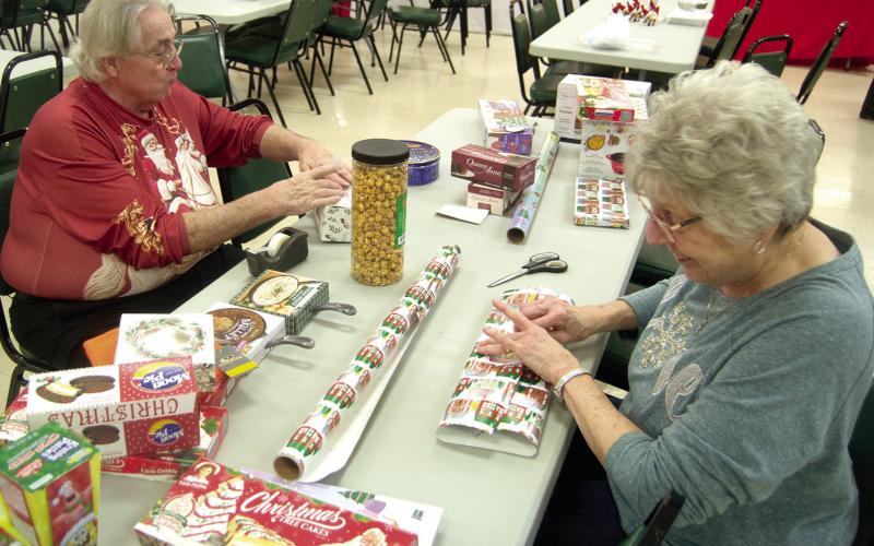 Preparing gifts for the Ugly Holiday Sweater contest winners were Steve Langerot and Donna Renn. The sweater show was held Sunday evening at St. Bridget’s Parish Hall.
