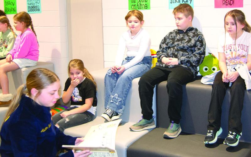 During FFA week at Columbus High School Addison Seitz reads to Verona Anderson, Piper Robinson, Trigger Allen and Ellie Skahan from Caitlin Creech’s third grade class at Central Elementary. Reading took place at the Central Elementary Library as part of FFA week. News Report photo by Tanya Woolsey.