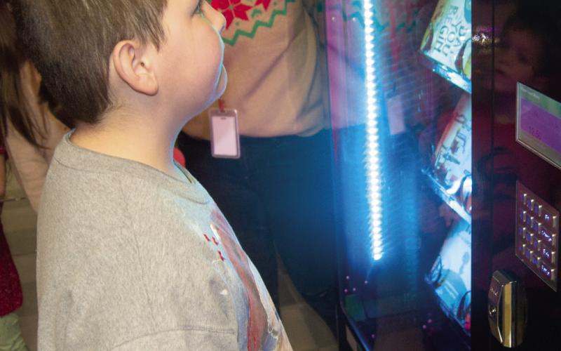 Choosing a book can be a bit difficult when there are so many choices. The new book vending machine at Central Elementary in Columbus has numerous options for young readers. Students can earn tokens to select a book which is then theirs to keep. Brayden Boeckman surveys the many books before making his choice.