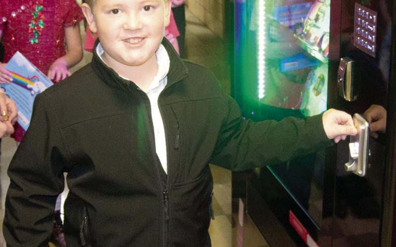 Kip Noel puts his token into the new book vending machine at Central Elementary in Columbus. A ribbon cutting was held Wednesday and students were on hand to purchase books with their tokens.