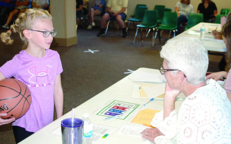 Reagan Holmes excitedly shows the judges her basketball outfit for the active wear category and explains to Dorothy Holmes about her outfit during the judging.