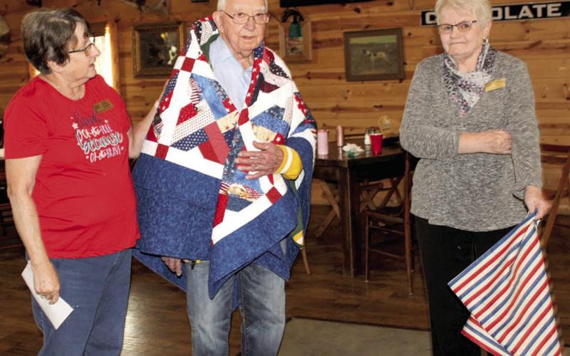 George Kasten (center) was recently honored with an early 90th birthday party. While his birthday is in December, the party was held early so his family in Wisconsin could be present. Kasten was also presented with a Quilt of Valor for his military service at the party. Kathy Lunday and Janie Fletcher presented the quilt.