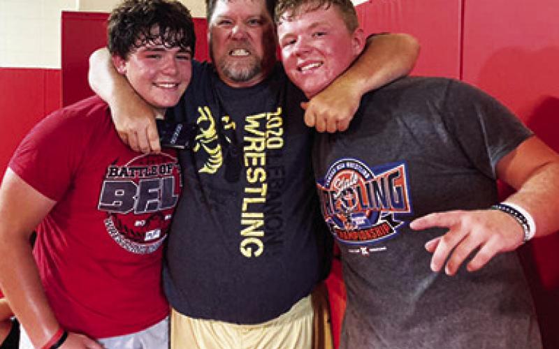 Titan Wrestlers Kash and Kanyen Smith are wrangled by Coach Randy Roark, 1992 Columbus Unified High School Graduate, after putting in time on the mat at the wrestling clinic in the high school gymnasium, July 19. Courtesy Photo.
