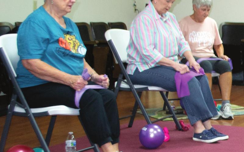 Local senior citizens prepare to perform flexibility exercises in the Columbus Hospitality Center, 516 N. Kansas. Each attendee uses the pictured balls, weights, stretch bands, and chairs to assist with their twice-weekly workout regiment. Pat Niggemann serves as the group’s leader. Photo by Jacob Spencer.