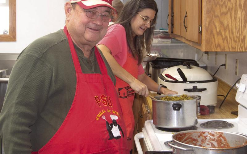 Spaghetti sauce is a specialty of Ron Holmes. He made his signature sauce for the recent fundraiser for Eva Maxton. While Holmes kept an eye on the sauce, Meghan Winden was taking care of the green beans. News Report photo by Shawn Churchill.