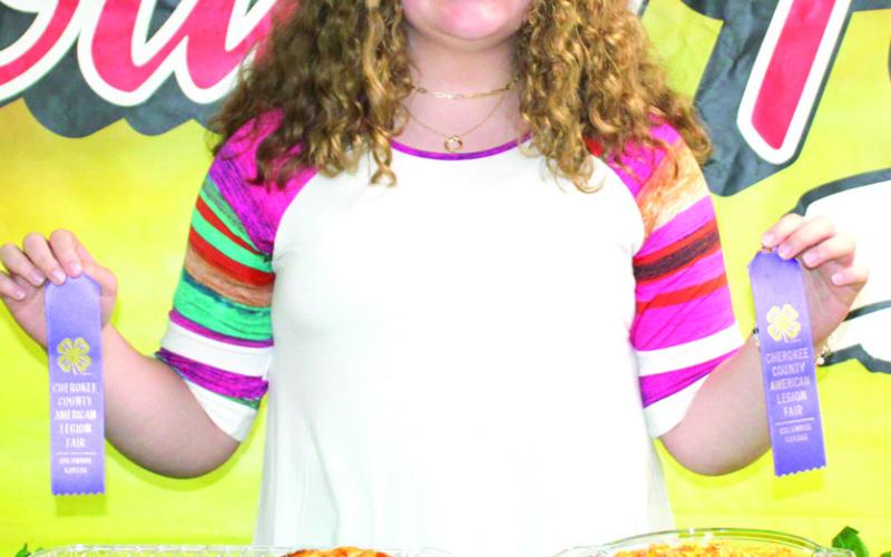 Alivia Perdue displays her two purple ribbons she won during the food show. Perdue is a member of Lone Elm Beavers.