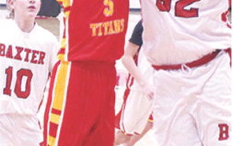Titan Seventh Grader, Hayden Kellogg, goes in for two of his ten, fourth quarter points to help elevate Columbus over their Baxter Springs hosts, 31-25, Monday. Lion Jaydan Biddle tries to defend the shot and Carsyn Kelly trails.