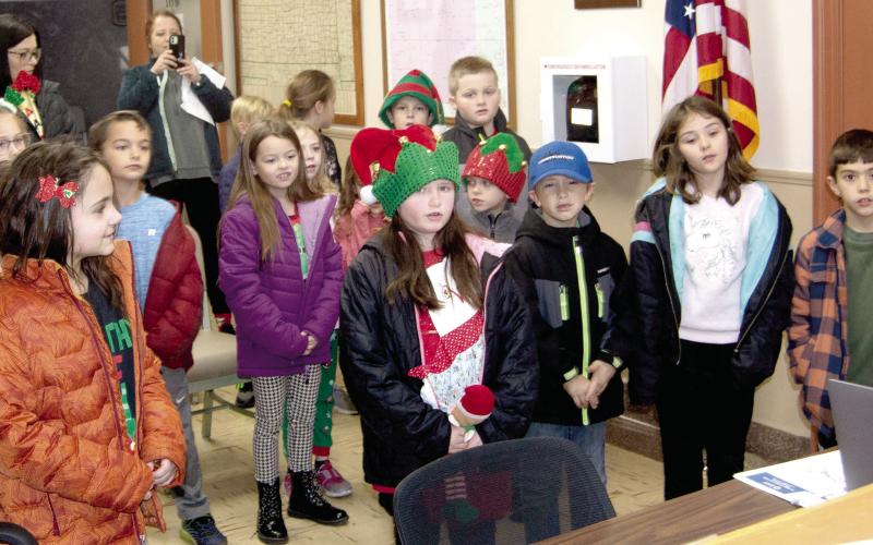 Melodies of Christmas filled the air in downtown Columbus Monday. Carolers, many dressed as elves, toured Columbus singing holiday tunes. Above Highland Elementary students in the classes of Becky Crystal and Debra Tocci sang for a business on the Square. Below, Tiara Tedlock’s class performed a medley of holiday music for the Cherokee County Commissioners.