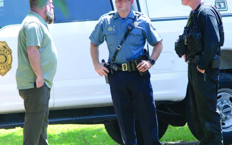 Left - Columbus Police Chief Jason Daniels talks with a highway patrol officer and an Explosive Ordinance Disposal officer at a house on West Maple Street, Thursday.