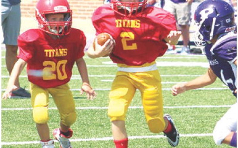 Jaxon Harper eludes a Pittsburg defender on his way to the goal line and into the end zone, Saturday, in the Columbus Mini Titan Third and Fourth Grade win, 26-14, over Pitt Mowen, Saturday at Hutchinson Field in their season opener at Pittsburg. Columbus will host Frontenac tomorrow at Titan Stadium. Kickoff will be at 10 a.m. Frontenac Nelson will be in town for a match up with the Titan Fifth and Sixth Grade Squad. Game time is set for noon.