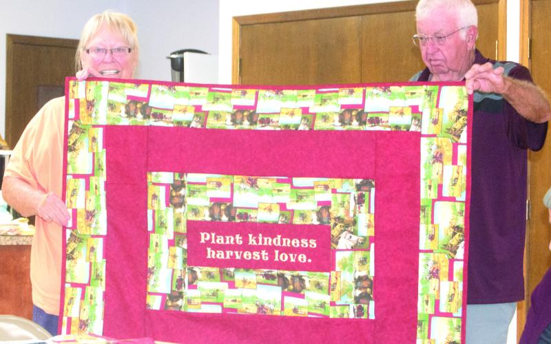 Former County 4-H Agent Martha Flanagan displays a quilt with the help of Art Roberts which has a farming theme. The quilt will be given away at the end of the Fair to the lucky ticket holder. Flanagan made the quilt specifically as a fund raiser for the Cherokee County Democrat Central Committee.