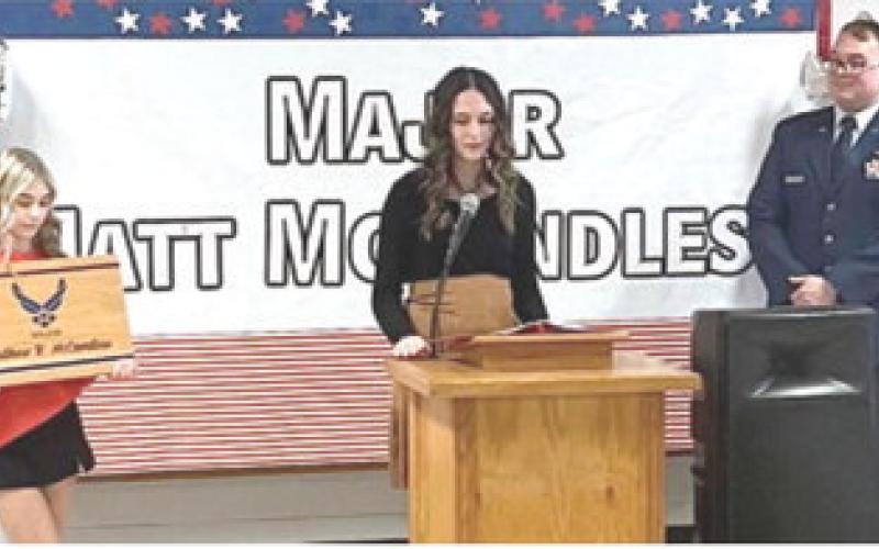 Receiving a commemorative cutting board (above) Matt McCandless, with his grandfather and wife Cassie, was honored Tuesday at the Baxter Springs Hometown Hero luncheon. (at right) McCandless spoke to those in attendance at the event. (Below) BHS students Natalie Mallory and Kadence Underhill presented the gifts.