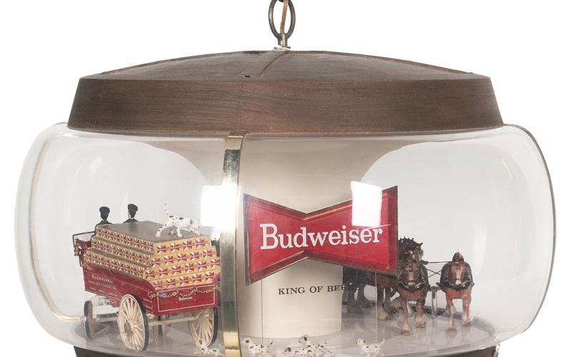 This advertising lamp includes figures of a team of horses pulling a beer cart with drivers, followed by a crowd of Dalmatians. Similar scenes may take place in real life on Budweiser’s promotional tours. The lamp with a moving wagon sold for $625.
