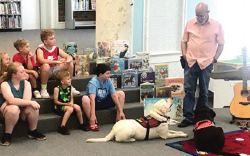 Children at the Johnston Public Library Tales and Tails program had a visit with musician Aaron Fowler and his service dogs Bella and Choco. Photo by Dee Riley.
