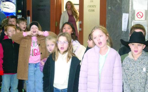 Second grade students in the classes of Tiara Tedlock and Lori Midgett sang, “Rudolf the Red Nosed Reindeer,” and other Christmas songs at the Courthouse December 17. News Report photo by Shawn Churchill.