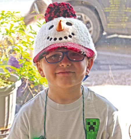 The weather might have been warm, but Manny Napier sported his snowman cap while the second grade classes sang carols around the square before Christmas break. News Report photo by Shawn Churchill.