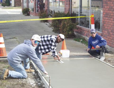 Construction crewmembers Andrew Heinlein, Johnathan Pinnegar, Ruben Reyes, and Robert Pinnegar (not pictured) are laying down the concrete for the new sidewalk between Westco and Tique-A-Bou. The up-keep of the town’s sidewalks is part of the City Council’s plan to improve the town’s upkeep. News Report photo by Shawn Churchill.