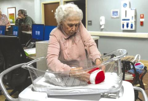 Columbus resident Ruby Wright places the red and white Valentine’s Day cap on Afredo Rodriguez. She has created over 2,000 caps for babies at Freeman Hospital in Joplin, Mo. She is working her way toward 3,000 now. Courtesy photo.