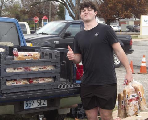 Jett Tanner was one of the Columbus High School students passing out food for the Thanksgiving boxes. Lines for the boxes were long and lined up several blocks from the pick up location. News Report photo by Shawn Churchill.