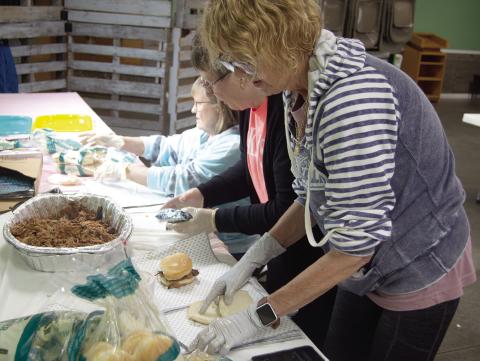 Workers were busy at the pulled pork fundraiser for Jenny Shilts recently. Marilyn Epler, Janice Maxton and Karen Karsten were preparing the sandwiches. News Report photo by Tanya Woolsey.