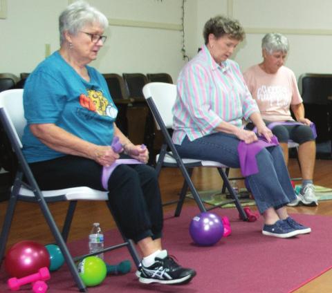 Local senior citizens prepare to perform flexibility exercises in the Columbus Hospitality Center, 516 N. Kansas. Each attendee uses the pictured balls, weights, stretch bands, and chairs to assist with their twice-weekly workout regiment. Pat Niggemann serves as the group’s leader. Photo by Jacob Spencer.