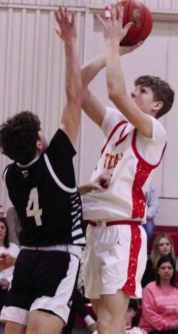 Titan Freshman, Jonas Stover, shoots for two points over Frontenac defender, Kane Mjelde, freshman, during the homecoming loss to the Raiders, 41-68, Friday at the CUHS Gymnasium.