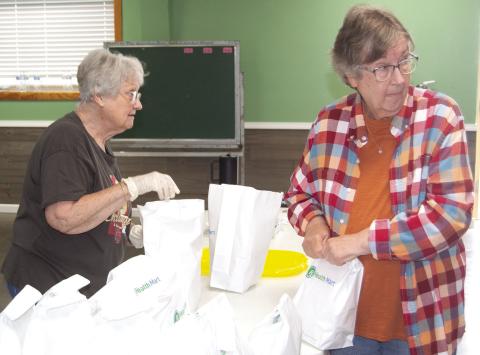 Linda Garrison and Cheryl Vanatta were bagging to go orders at the fundraiser for Jenny Shilts recently. News Report photo by Tanya Woolsey.