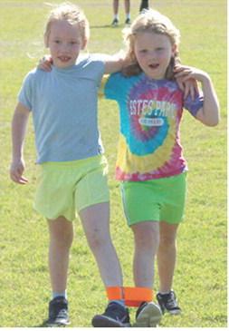 Paislee Hodgson and Sophia Kitch took first place in their heat of the kindergarten three-legged race at the all school track meet, Friday.