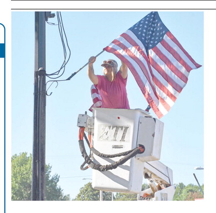 Though not a patriotic holiday, City of Columbus employee Kasie England worked Friday placing the U.S. flags on light poles down Maple Street and around the square for the Labor Day holiday.