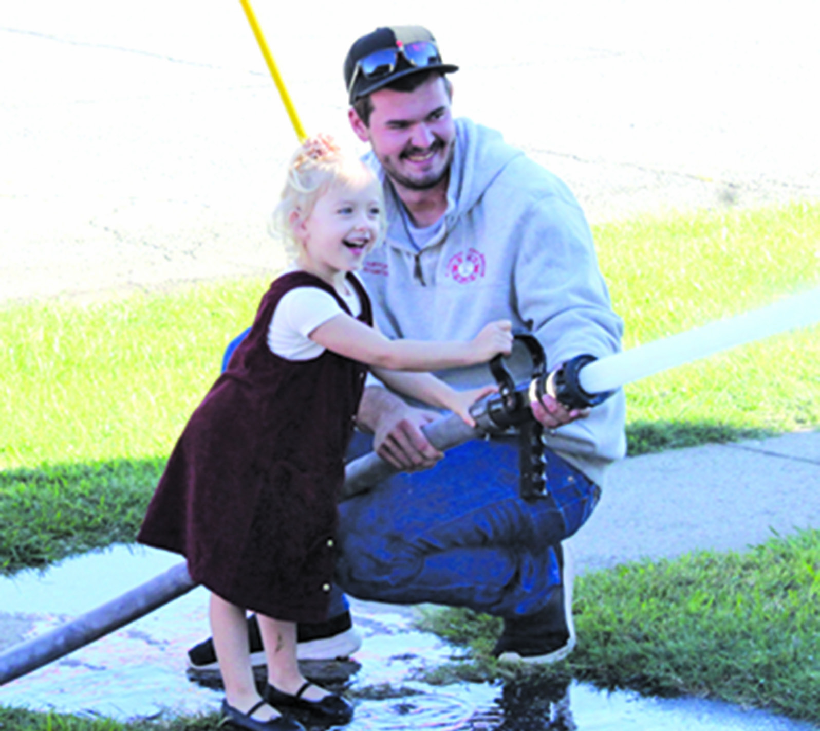 Columbus Firefighter Hunter Burton helps Eleanor Otto aim the fire hose during Fire Prevention Week.