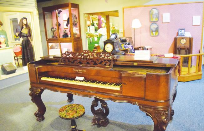 An antique piano sits in the center of several varied displays inside the Baxter Springs Heritage Center.
