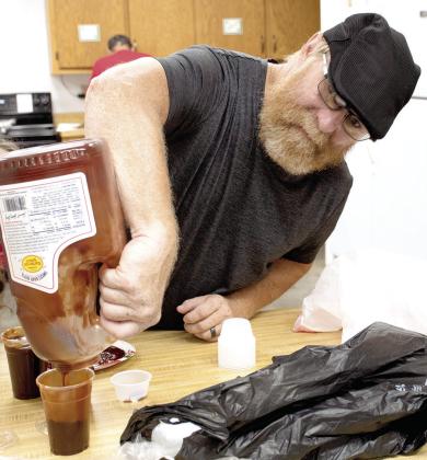 Aron Davolt worked to prepare barbecue sauce containers for to-go meals during the benefit dinner held for longtime Columbus barber Ed Semonick June 17.