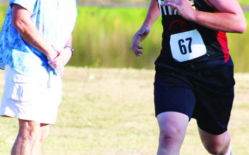 Dr. Brian Smith, fresh off injury, cheers for Josh Shultz, sophomore, as he completes the boys JV 5K race at the Columbus Cross Country Invitational, Tuesday at the Brush Creek Golf Course.
