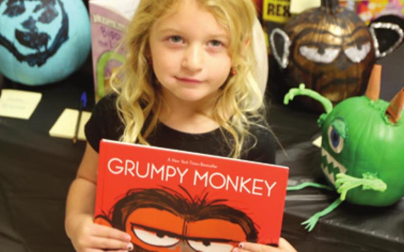 Reading the book “Grumpy Monkey” gave Andi Parsons the idea for decorating her pumpkin with the monkey eyes. The decorated pumpkin is directly behind Andi in the photo.