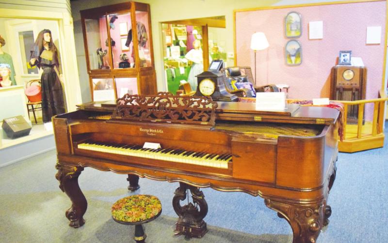 An antique piano sits in the center of several varied displays inside the Baxter Springs Heritage Center.