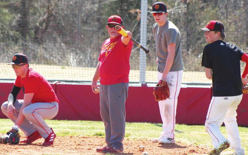 Titan Head Baseball Coach, Mick Tedlock, points out what he wants during practice, Wednesday, at Bomber Field in the Community Field Ball Park. Junior, Landin Midgett, junior, Kayden Cox, and freshman, Jace Midgett take their turn in rotation at catcher. The Titans open their 2022 season at the Wyandotte, Okla. Festival, tomorrow. First pitch will be at 12:15 p.m. Game two starts at 4:45 p.m.