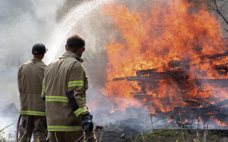 What started as a small fire Monday afternoon quickly spread to engulf multipole acres including a file of more than a hundred railroad ties. Columbus Fire Fighters Kale Kitterman and Cody Burton work to contain the large fire as part of a six-man, three apparatus crew that responded to the fire.