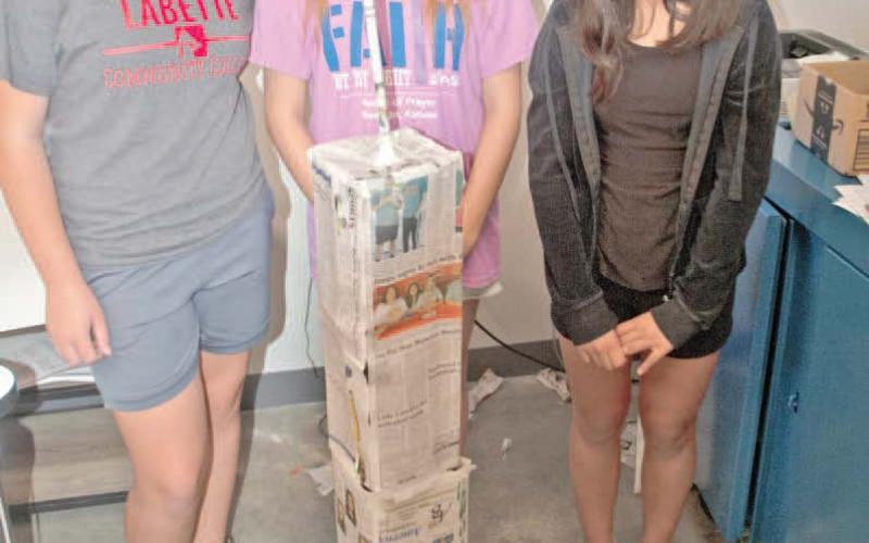 Standing behind their paper tower, Temperance Goff, Grace Alderman and Emily Soto, were first finished with the tower likeness including the antenna. This tower was judged among the best.