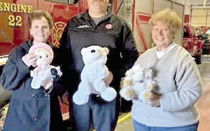 Representing Columbus Fire Department, Korey Lucian (center), accepted stuffed animals from members of the Cherokee County Retired School Personnel. The toys will be used to comfort children in emergency situations. Ann Thiele and Athena McColm, as well as Mary Torchia (not pictured) handed out the toys. Courtesy photo.