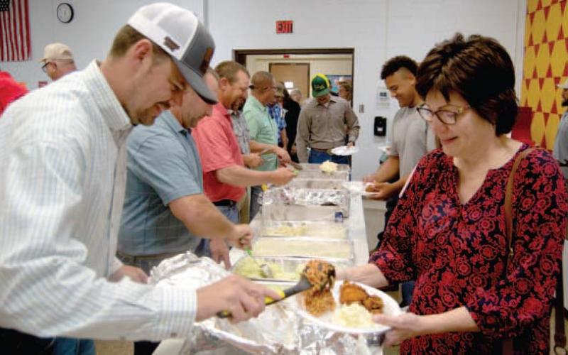 Farmer’s Cooperative Board member Kolby Chrz serves chicken to Kelly Robison at the 75 annual meeting of the local cooperative. The board members and employees serve the members of the coop.