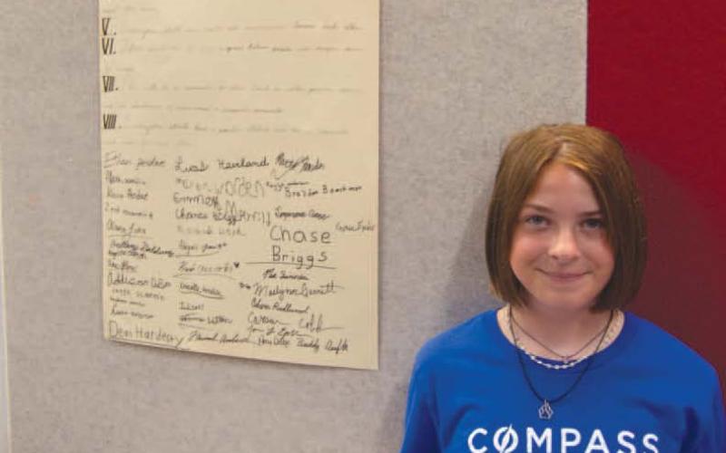 Standing beside the Classroom Constitution developed by the Compass Academy students during their recent session. Misty Daniels is pictured by the Civics work.