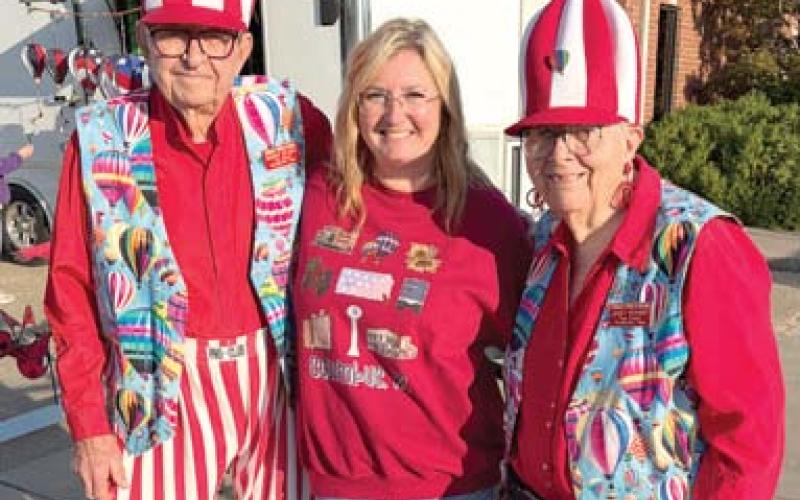 Bringing a colorful bunch of visitors to the Columbus Days celebration Monroe and Janet Neihart of Neihart Tours came to Columbus attired in balloon regatta dress. The Braddyville, Iowa tour spent the week-end in town. Monica Delmont, Chamber of Commerce Director, spent some time visiting with the couple. Courtesy photo.