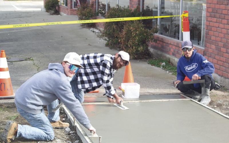 Construction crewmembers Andrew Heinlein, Johnathan Pinnegar, Ruben Reyes, and Robert Pinnegar (not pictured) are laying down the concrete for the new sidewalk between Westco and Tique-A-Bou. The up-keep of the town’s sidewalks is part of the City Council’s plan to improve the town’s upkeep. News Report photo by Shawn Churchill.