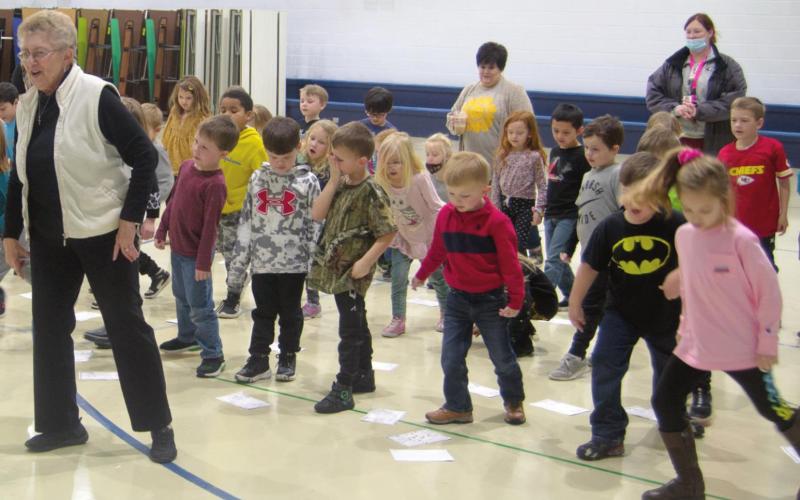 Kindergarten students at Spring Grove Primary School in Galena celebrate Kansas Day with retired teacher Nancy Bash. The group dances to the “Hokey Pokey” after learning about the state’s official animals, crops and singing “Home on the Range” together. Photo by Jacob Spencer