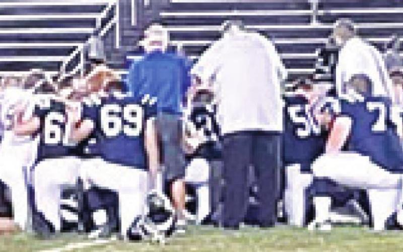 Players and coaches for the Riverton Rams and Galena Bulldogs Football Teams knelt and prayed together for Riverton Head Basketball Coach, Brandon Pate, following their CNC League game in Galena, Friday. Coach Pate’s wife, Paige Christiansen Pate teaches Spanish in both school districts. Galena won the contest, 42-24. Courtesy Photo.