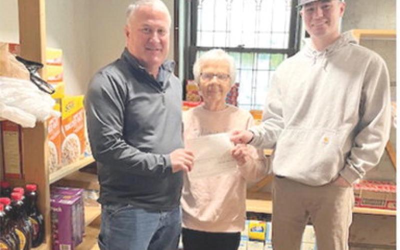 Gene Hamilton and Cameron Draeger with Optic Communications presented Sharon Draeger at the First United Methodist Church food pantry with a $1,000 donation. Courtesy photo.