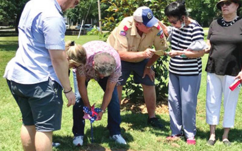 Oren Brittle Troop 15 Scoutmaster, presented Charlene Button with a gift at the memorial ceremony and tree planting for Charlie Button held Saturday. A magnolia tree and memorial stone were placed on the lawn of the Johnston Public Library. Photo by Dee Riley.