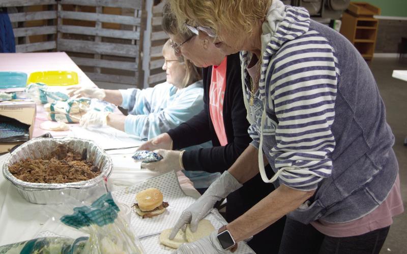 Workers were busy at the pulled pork fundraiser for Jenny Shilts recently. Marilyn Epler, Janice Maxton and Karen Karsten were preparing the sandwiches. News Report photo by Tanya Woolsey.