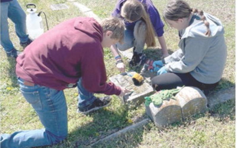 Seventh grade students at Southeast Middle School participated in a day of service April 8. Gavin Potts, Kylee Emerson, and Kinzey Mitchell were cleaning headstones at Cherokee Cemetery. Students also picked up litter on Highway 7. Sons and Daughters of the American Revolution assisted with supplies explained historical preservation techniques. Courtesy photo.